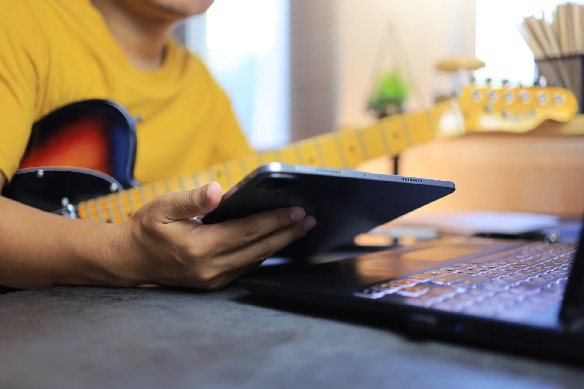 Man using tablet and computer with guitar